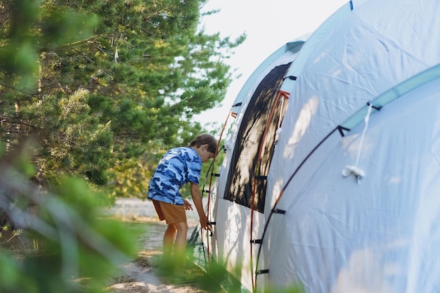 텐트를 치는 것을 돕는 귀여운 백인 소년 가족 캠핑 개념