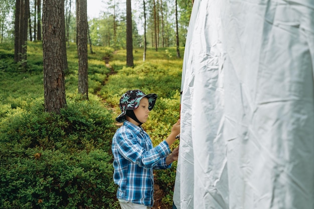 Cute little caucasian boy putting up a tent family camping concept