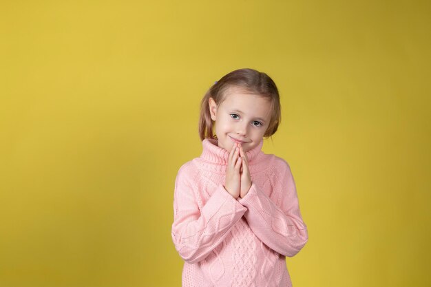 Cute little caucasian elementary age school girl looking at the camera on yellow