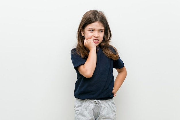 Cute little caucasian girl biting fingernails, nervous and very anxious.