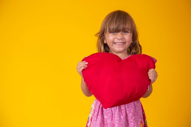Cute little caucasian girl holding a red plush heart Feelings romance love concept