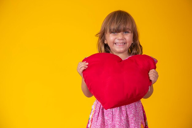 Cute little caucasian girl holding a red plush heart feelings romance love concept