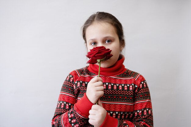 Cute little Caucasian girl in red dress with rose. valentine day.