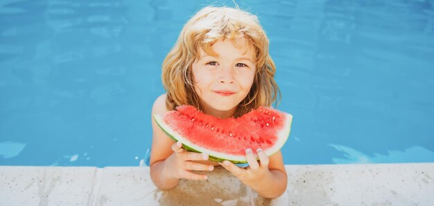 スイカを食べるプールでかわいい男の子はトロピカルフルーツの夏の子供たちを食べることをお楽しみください