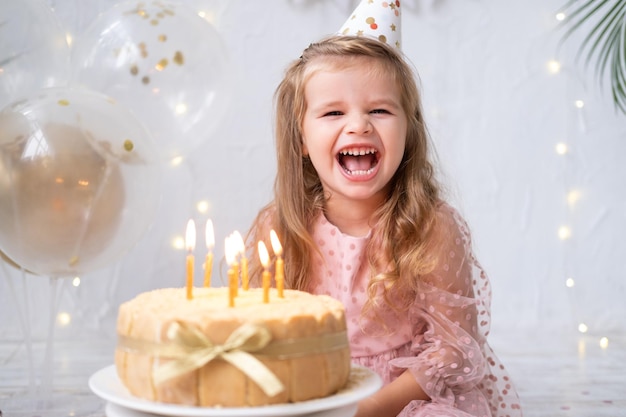 Cute little child girl blowing candles on birthday cake and celebrating birthday