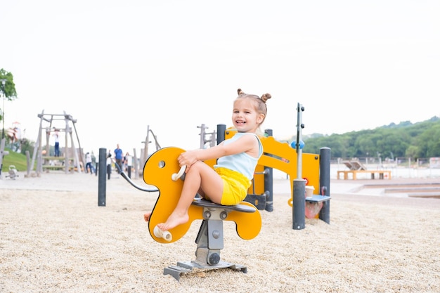 cute little child girl in colorful clothes playing on kids playground in summer day