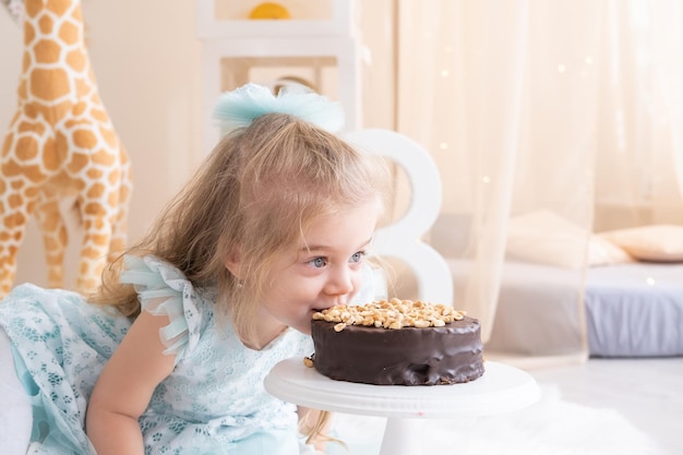 Photo cute little child girl eating chocolate birthday cake and celebrating birthday