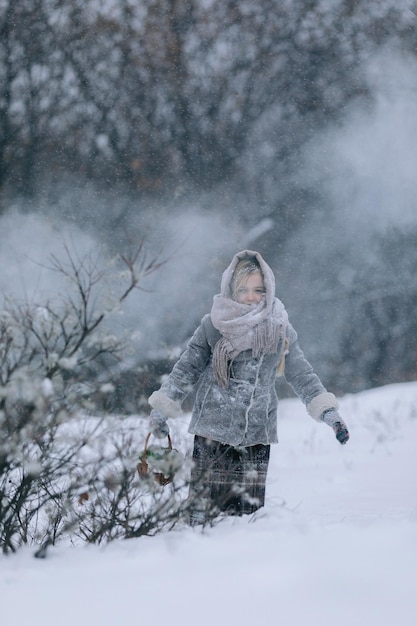 사진 겨울에 눈이 내리고 폭풍우가 오는 숲에서 귀여운 어린 소녀