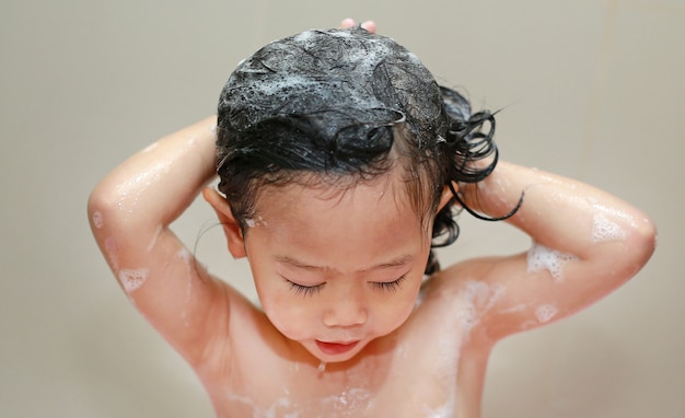 거품 목욕에 머리카락을 세척하는 귀여운 작은 아이 소녀.