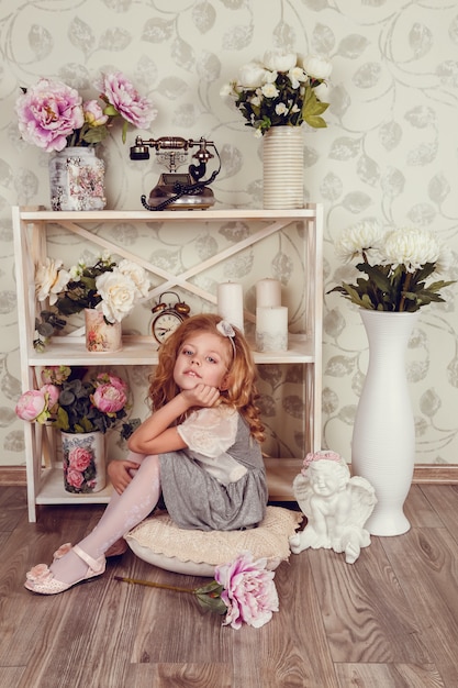 Photo cute little child girl with spring flowers, happy baby girl with basket of flowers.