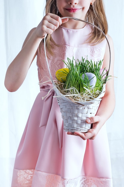 Cute little child holding basket with painted eggs on Easter day.