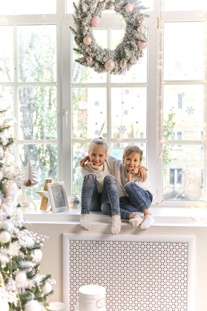 Cute little child on window sill at home waiting for Christmas celebration