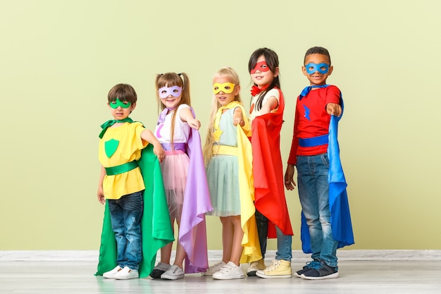 Photo cute little children dressed as superheroes near color wall