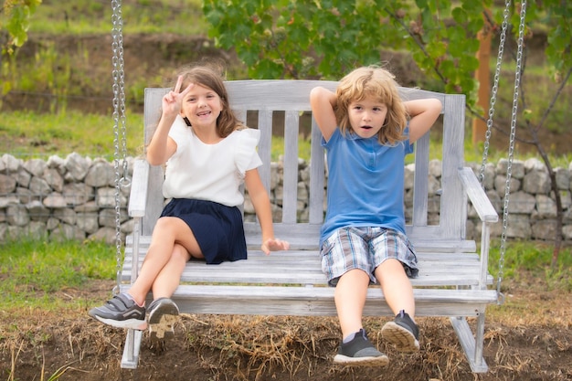 Cute little children playing and swinging outdoors portrait of two happy young kids at the summer park