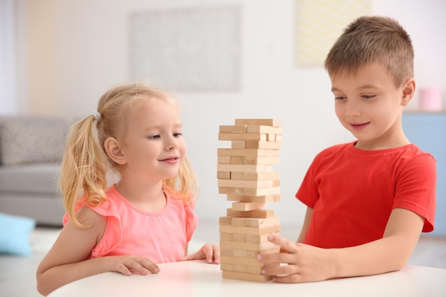 Cute little children playing with building blocks at home