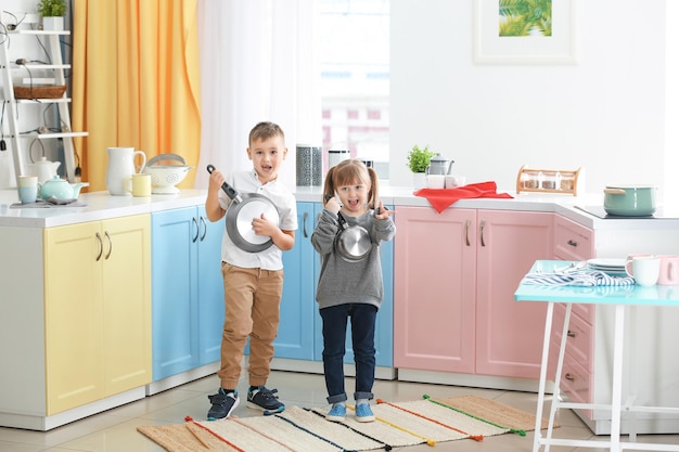 Cute little children playing with kitchenware as musical band at home