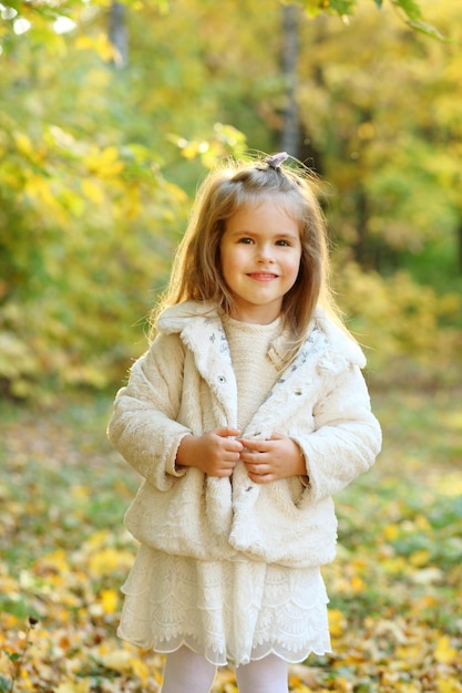 Cute little daughter standing in autumn park a