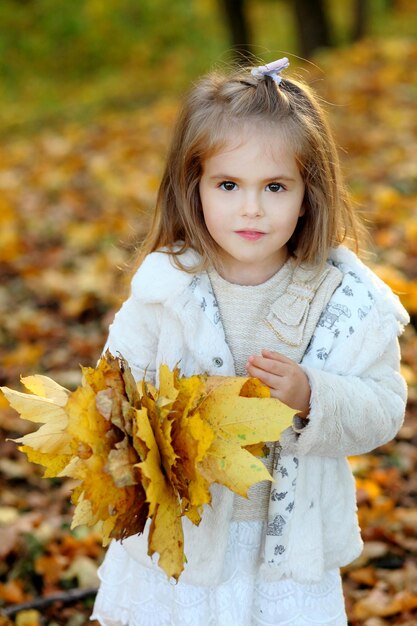 Cute little daughter standing in autumn park a