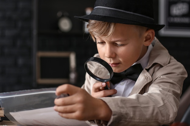 Cute little detective working with evidence at table