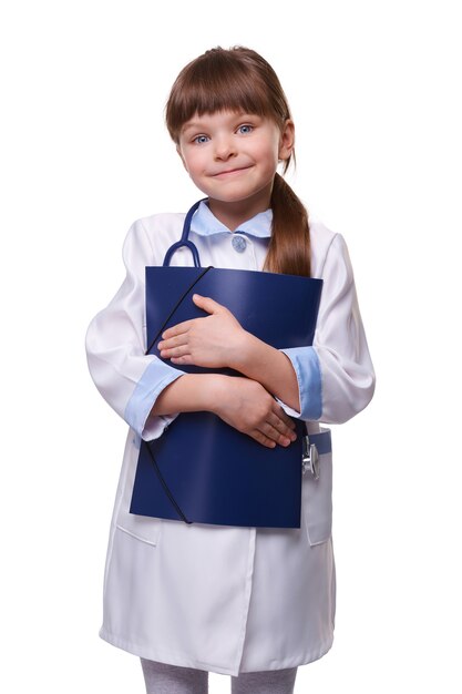 聴診器と白い医療コートを着ているかわいい小さな医者の女の子は、白い孤立した背景のフォルダーを保持します。