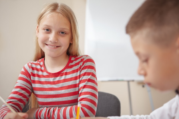 Cute little elementary school students drawing in class together