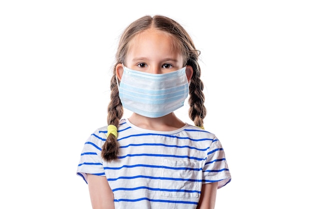 Cute little european girl wearing a disposable hygienic face mask isolated on white background. Prevention of spreading the coronavirus COVID-19 concept.