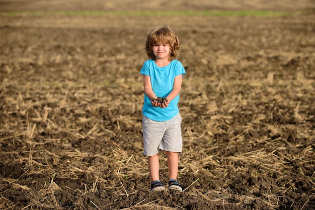 Cute little farmer working on field humus soil