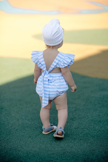 Cute little girl 1 year old on the beach at the resort in summer in a trendy outfit