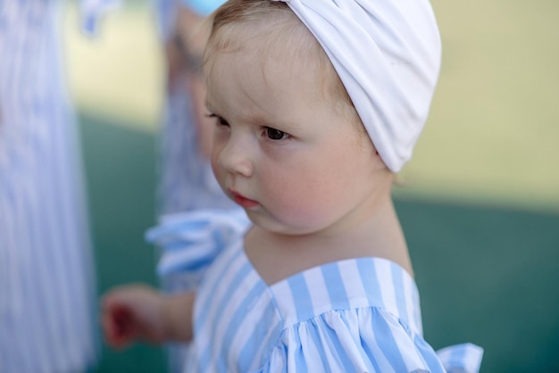 Cute little girl 1 year old on the beach at the resort in summer in a trendy outfit