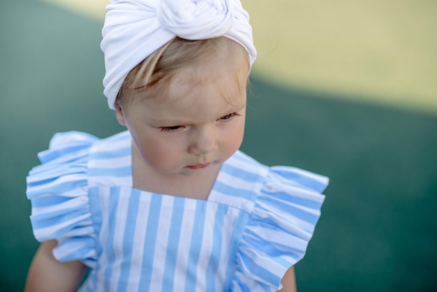 Cute little girl 1 year old on the beach at the resort in summer in a trendy outfit