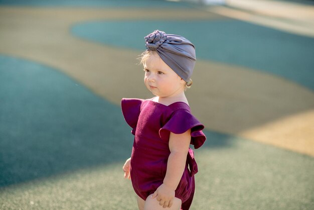 Cute little girl 1 year old on the beach at the resort in summer in a trendy outfit