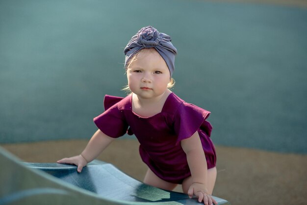 Cute little girl 1 year old on the beach at the resort in summer in a trendy outfit