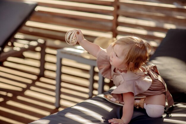 Cute little girl 1 year old on the beach at the resort in summer in a trendy outfit