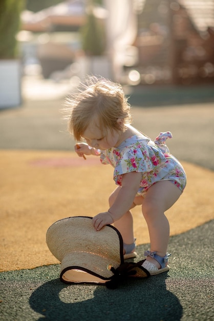 Cute little girl 1 year old on the beach at the resort in summer in a trendy outfit