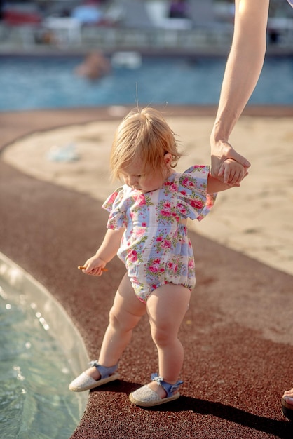 Cute little girl 1 year old on the beach at the resort in summer in a trendy outfit