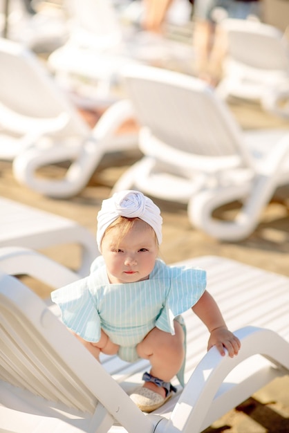 Cute little girl 1 year old on the beach at the resort in summer in a trendy outfit