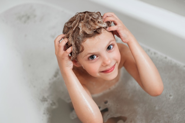 cute little girl, 6 years old, washes his head, head in foam