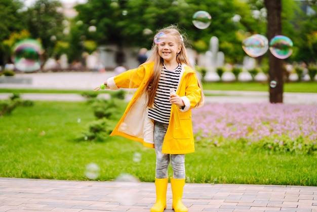 Cute little girl in autumn on a walk blowing soap bubbles Childhood active rest lifestyle concept