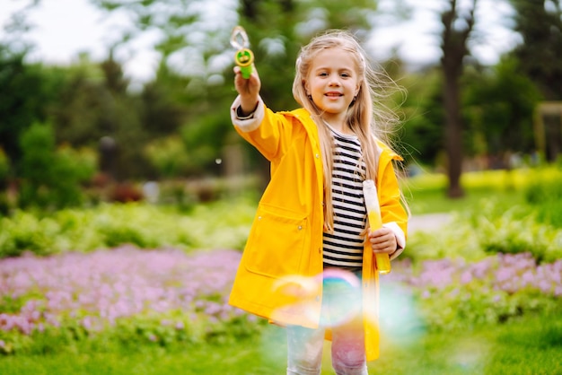 Cute little girl in autumn on a walk blowing soap bubbles Childhood active rest lifestyle concept.