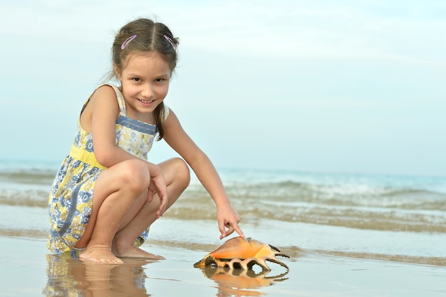 Photo cute little girl on beach with shell