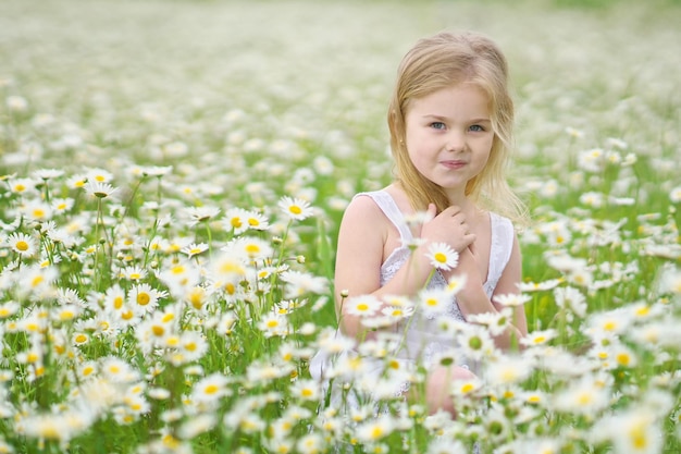 Cute little girl in big camomile meadow