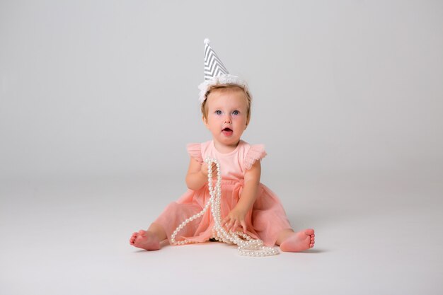 Cute little girl in birthday cap on light