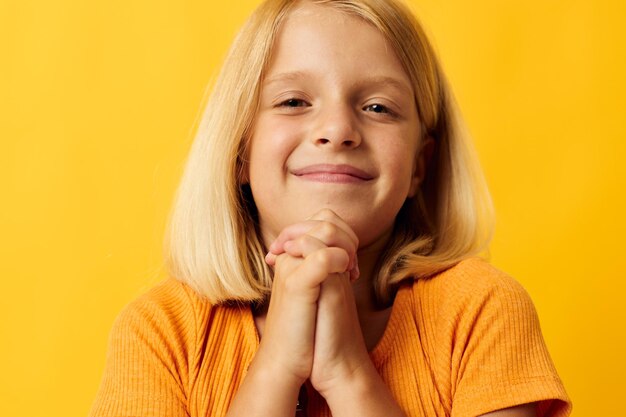 Cute little girl blonde straight hair posing smile fun yellow background unaltered