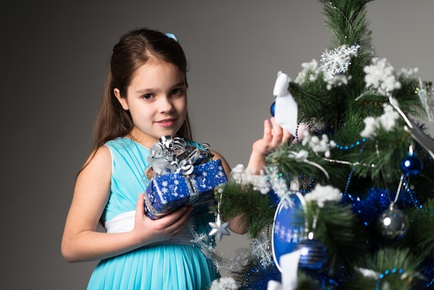 Cute little girl in a blue dress holds a gift