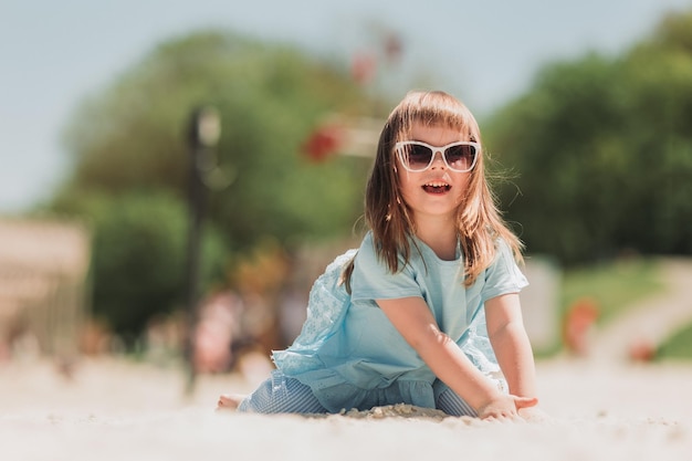милая маленькая девочка в голубом платье расплачивается на пляже