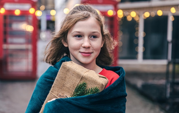 Bambina carina su uno sfondo sfocato di cabine telefoniche rosse e con bokeh