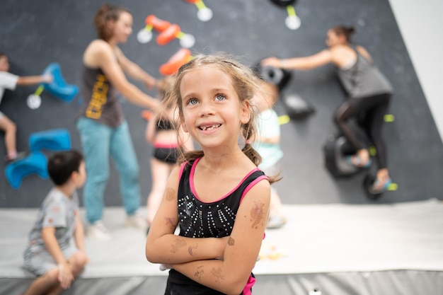 Cute little girl climber standing arms crossed in sports center