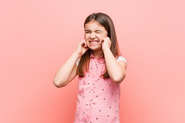 Cute little girl covering ears with his hands.