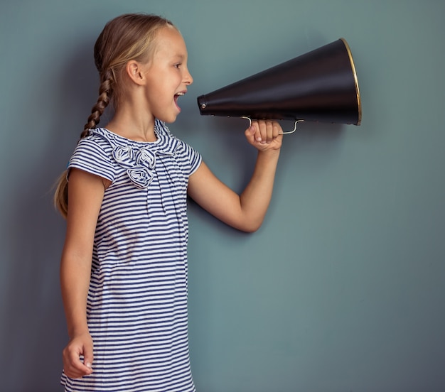 Cute little girl in cute dress screaming into loudspeaker.