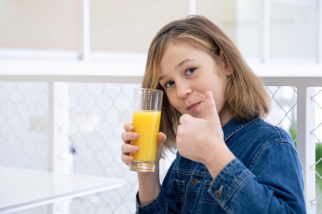 Cute little girl in a denim shirt in a cafe with a glass of juice